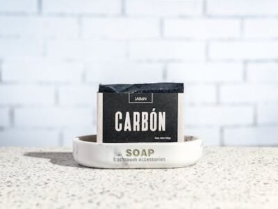 Close-up of handcrafted charcoal soap on a marble tray against a white brick wall.