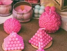 A selection of vibrant pink handmade candles in various shapes, perfect for home decor.