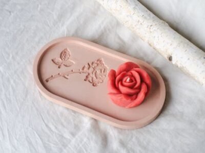 Artistic pink ceramic tray featuring a red rose and butterfly relief, perfect for decor inspiration.