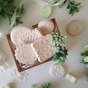 A top view of decorative soaps in a wooden box surrounded by greenery, perfect for an aesthetic still life.
